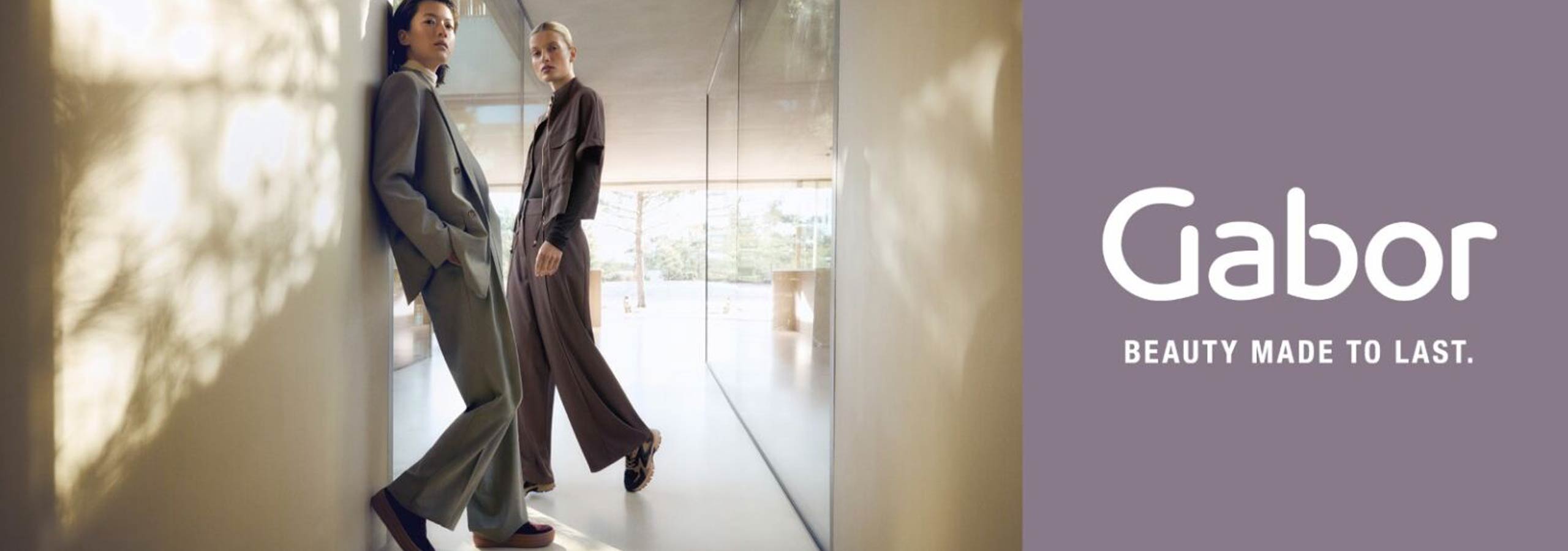 Two women in stylish outfits standing in a modern interior setting with 'Gabor' branding.